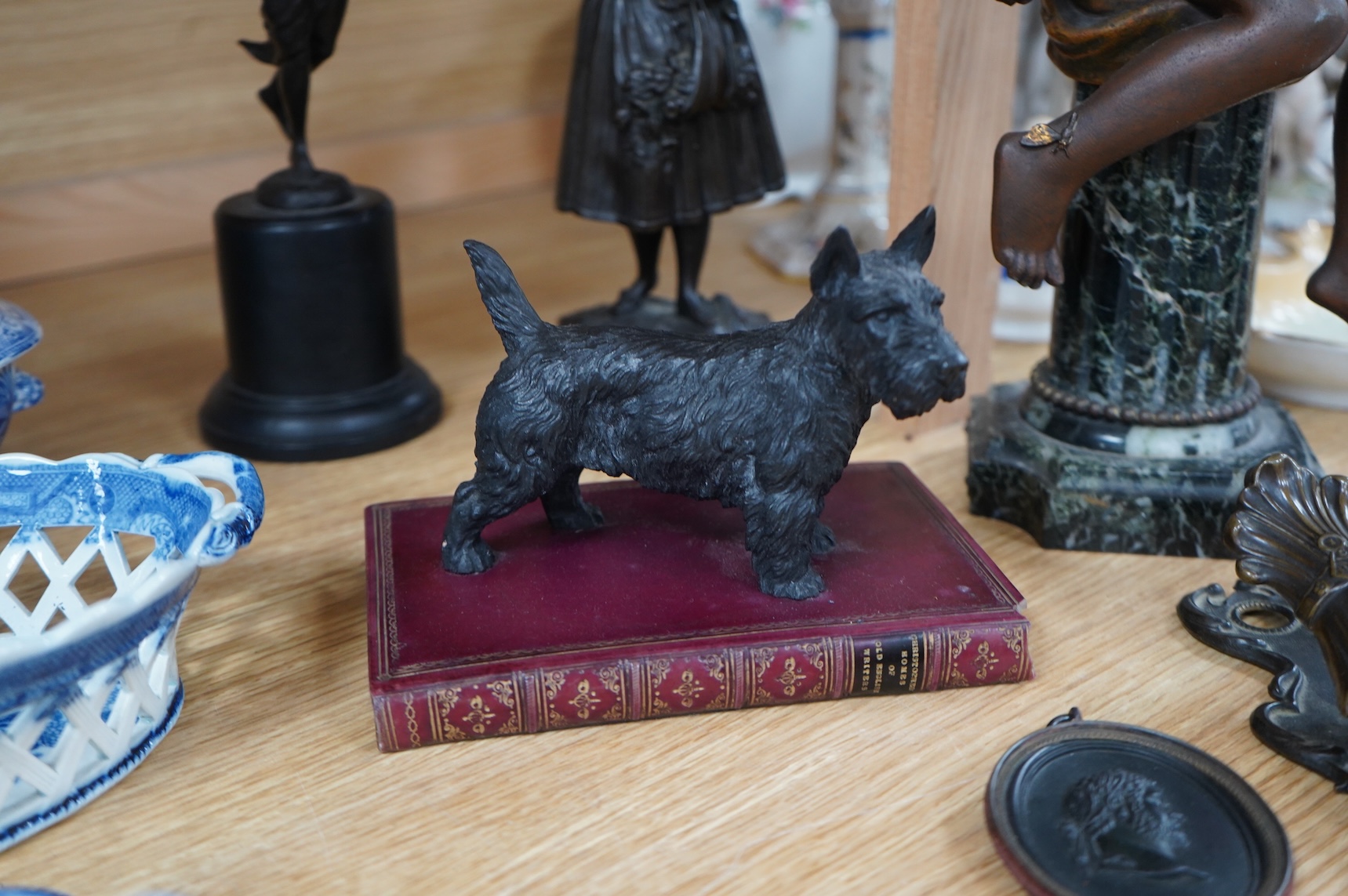A bronzed spelter angel on column plinth, 38cm high, two other figures, a model of a dog on a book, a letter clip and an oval classical plaque. (6).